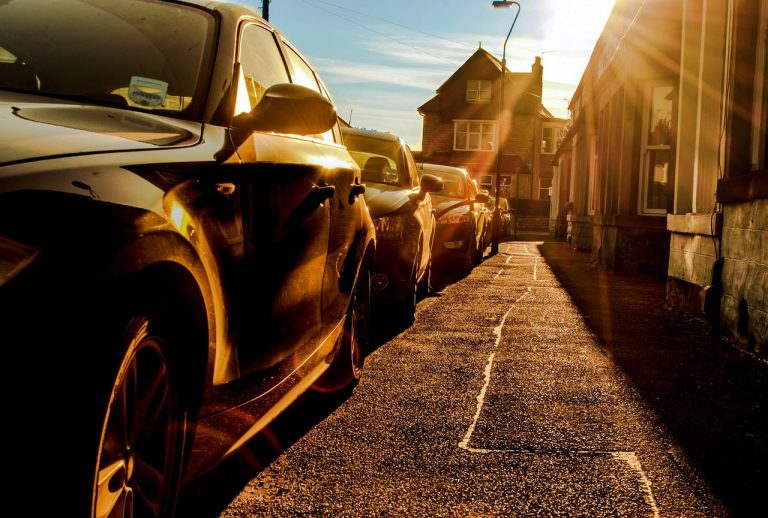 Parkende Autos auf der Straße in der flimmernden Sonne als Symbol für Hitze im Auto