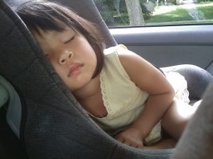 Schlafendes Mädchen im Kindersitz im Auto im Sommer
