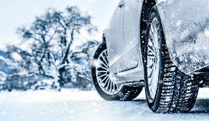 Blick auf Winterreifen an einem Auto auf schneebedeckter Fläche